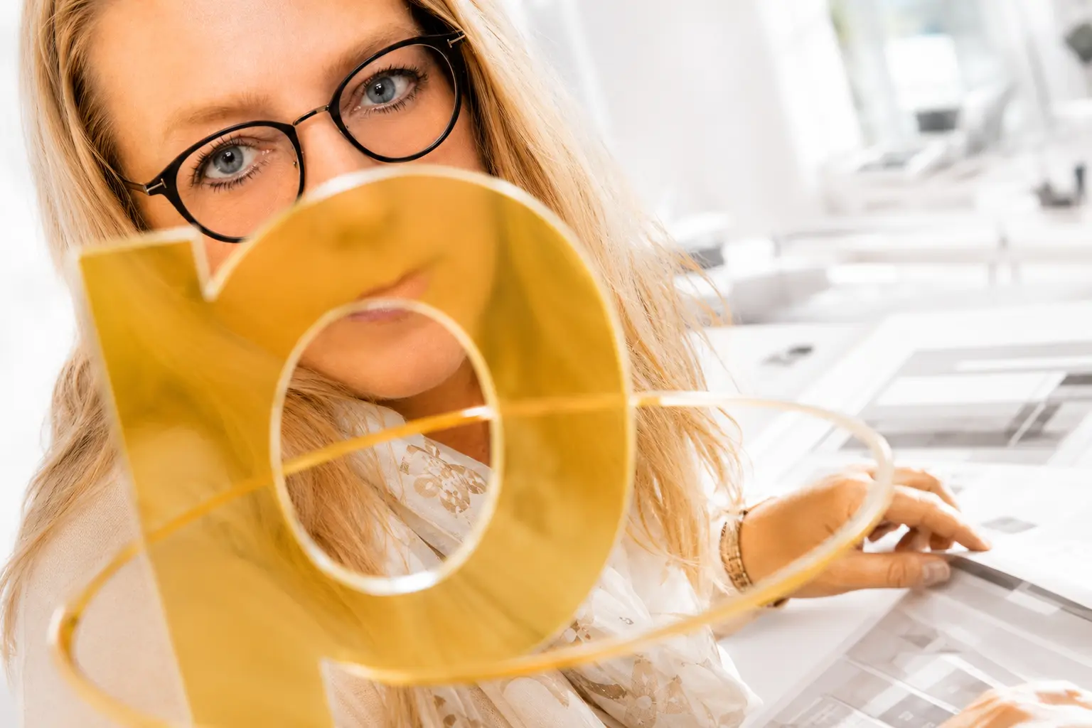 Helles Fragmentporträt von Anja hinter einem transparenten gelben P und Layoutentwürfen.