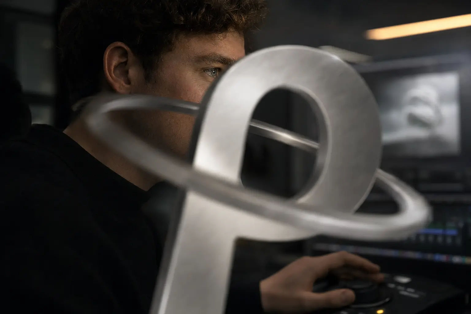 Dunkles menschliches Fragmentporträt im Motion-Studio hinter einem bewegten metallischen P.